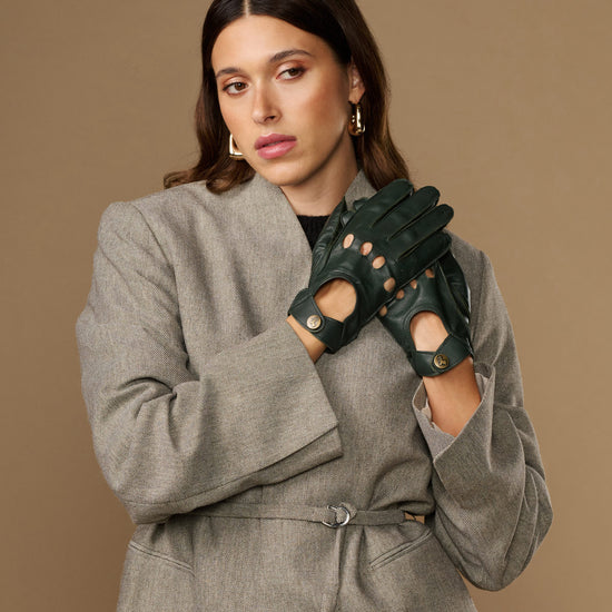 Dark green leather driving gloves with five-finger cutouts and round gold emblems