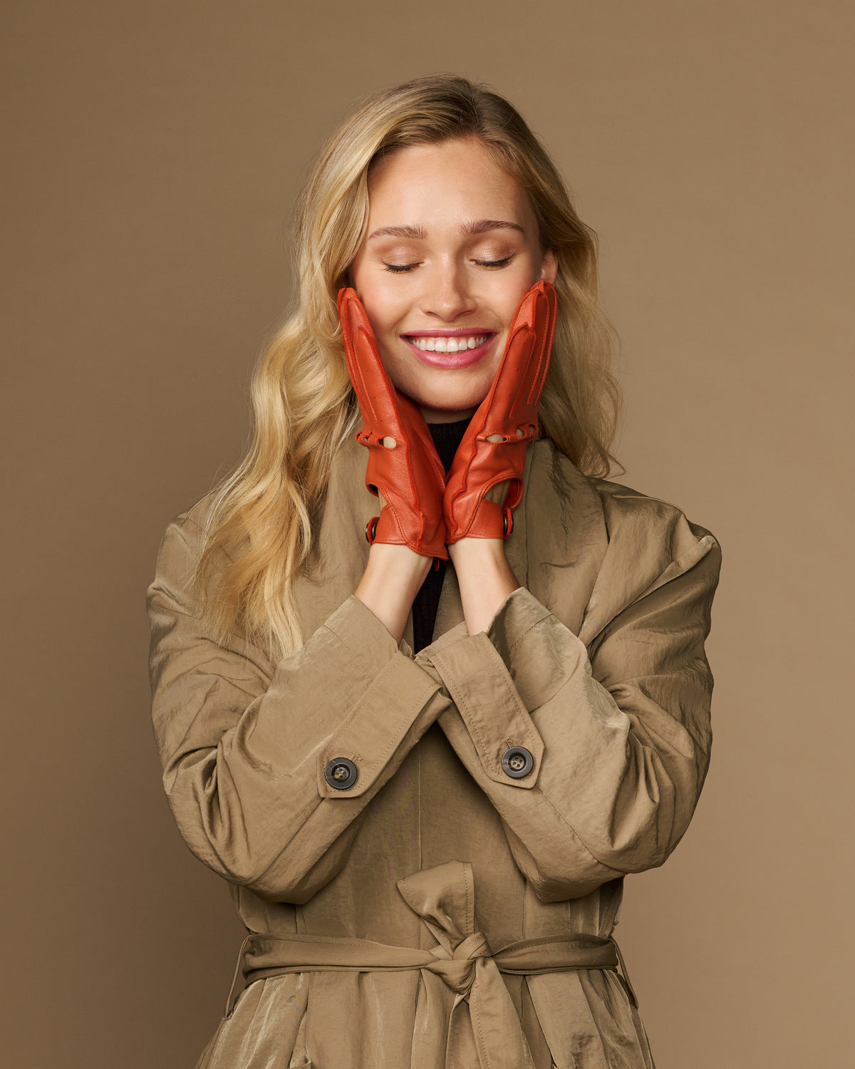 Women's orange lambskin driving gloves on hands, perforated touchscreen fingertips