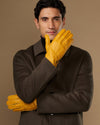 Yellow leather gloves on model with one glove raised near face