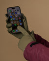 Olive green activity gloves operate a smartphone with touchscreen fingertips