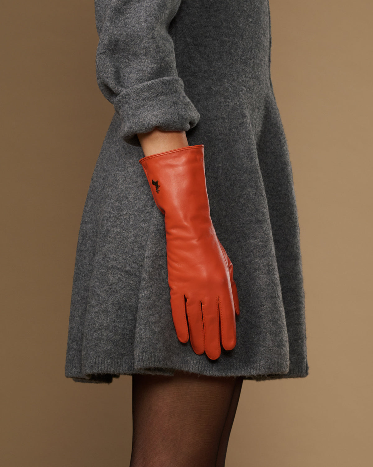 Long orange leather glove with padded wrist and finger seams, cuff extends past sleeve