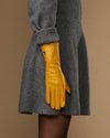 Yellow extra-long leather glove paired with matching cuff logo; finger tips angled down