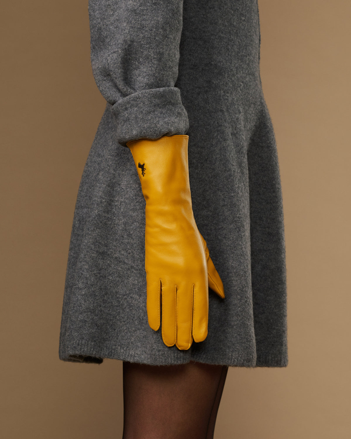 Yellow extra-long leather glove paired with matching cuff logo; finger tips angled down