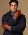 Cognac leather gloves with blue wool lining cuff, one hand raised