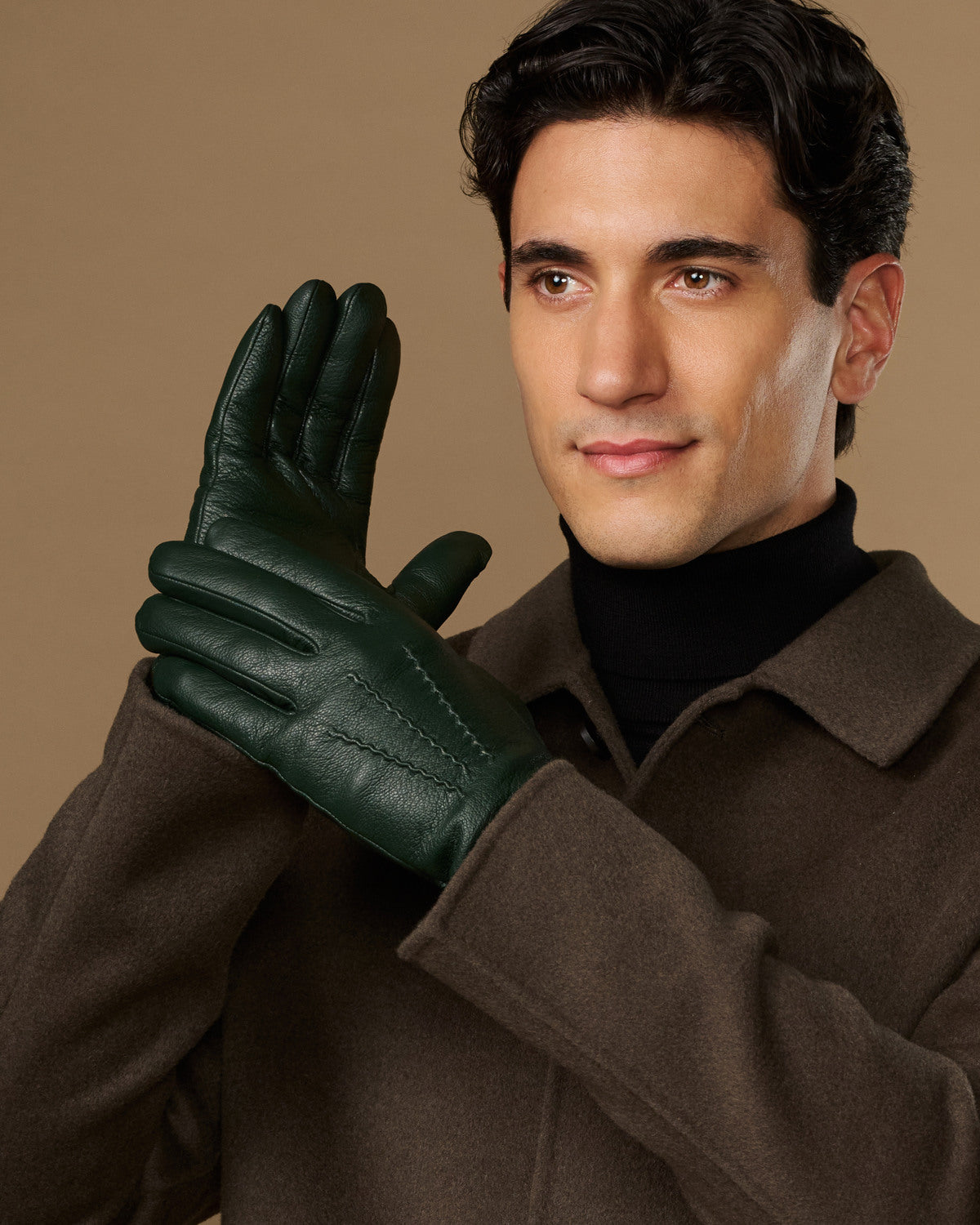 Men's dark green leather gloves, raised hand pose with stitched back