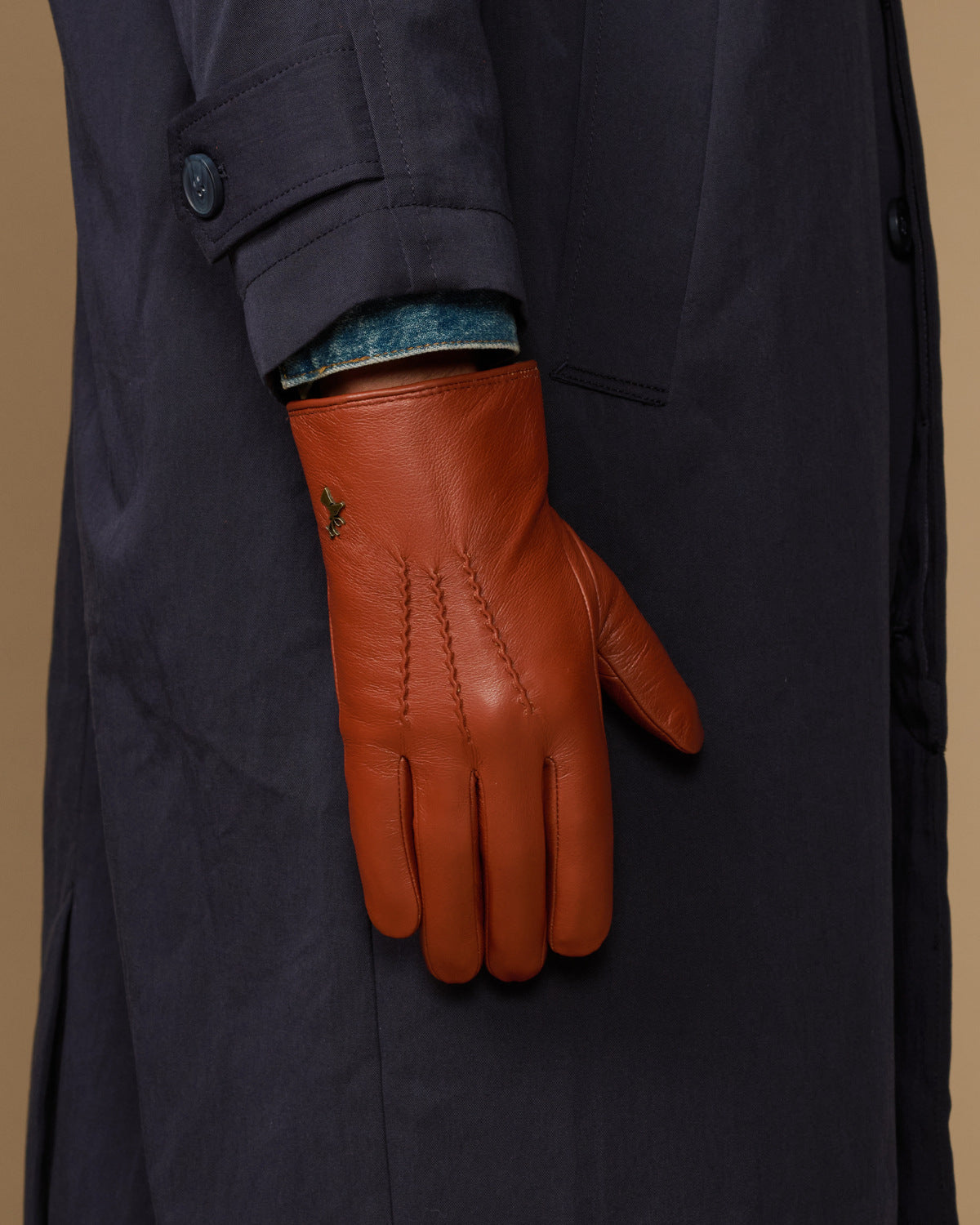 Men's cognac goatskin glove on navy coat sleeve, blue lambswool lining