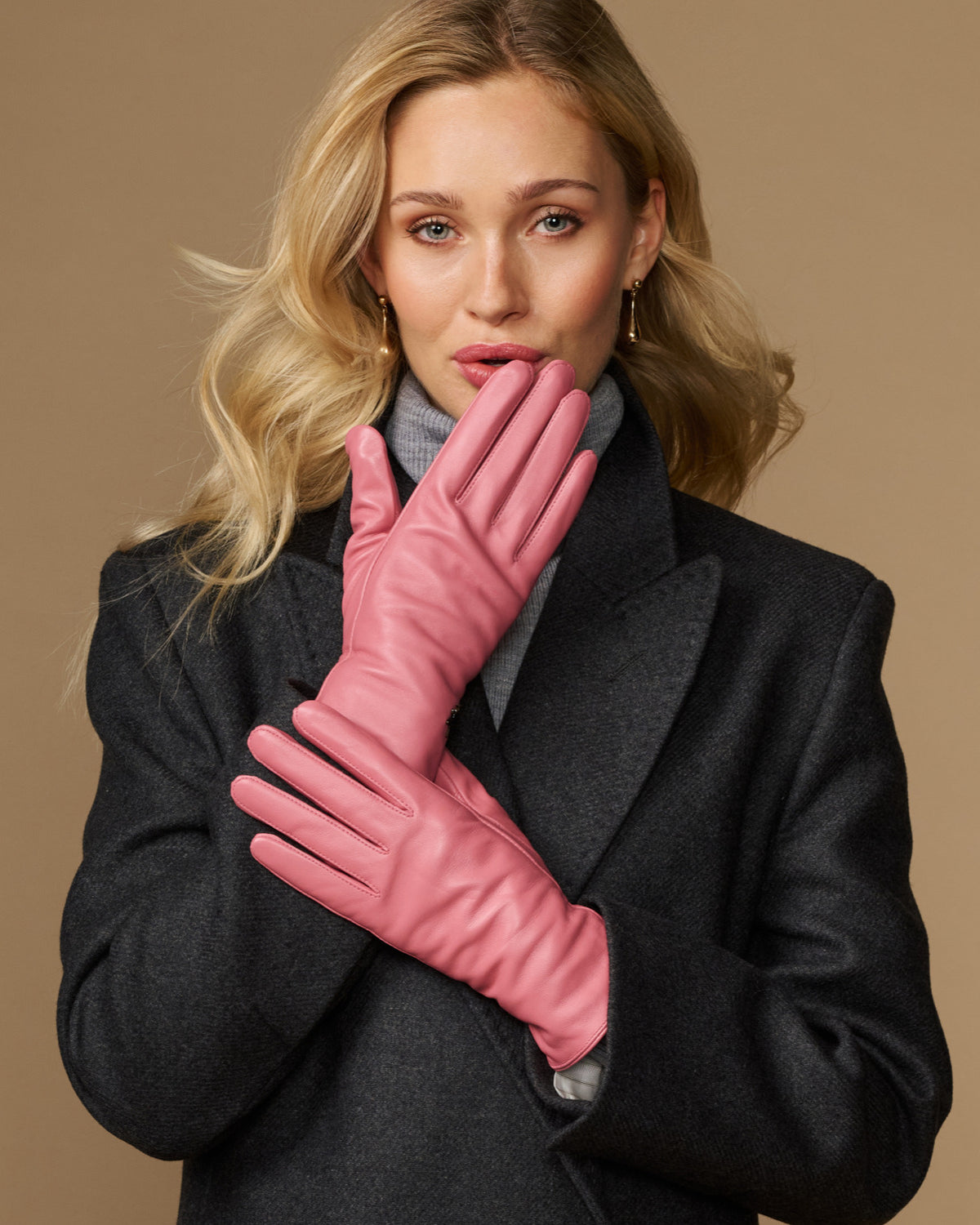 Women’s pink leather gloves held together, showing smooth back and stitched fingers