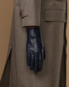 Navy leather glove with cuff detail, worn under a plaid coat sleeve