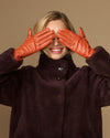 Lauren orange lambskin leather gloves with touchscreen tips, silk-lined, two hands raised