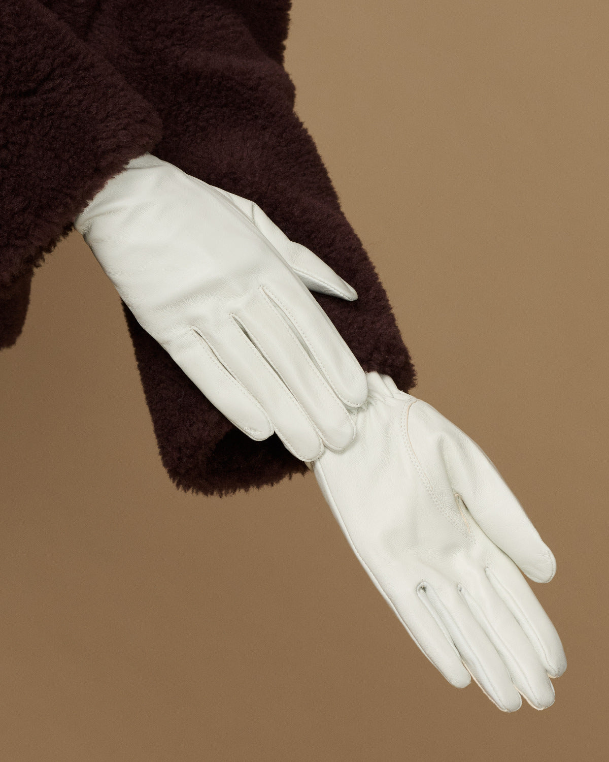 Women’s white leather gloves showing palm and stitched fingertips with slim wrist opening