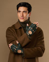 Dark green fingerless driving gloves with perforated knuckles and wrist openings, worn on both hands
