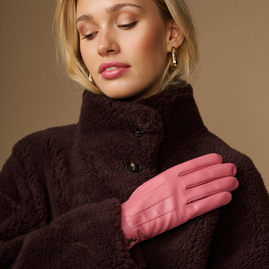 Pink leather gloves with dark fleece sherpa lining, one hand across chest
