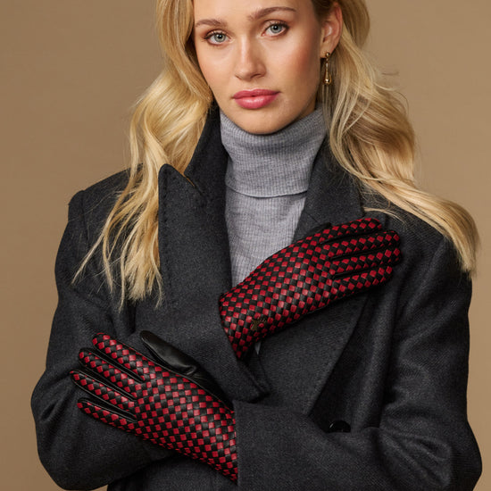 Women's black leather gloves with red and black checkered lining, worn with cuffs