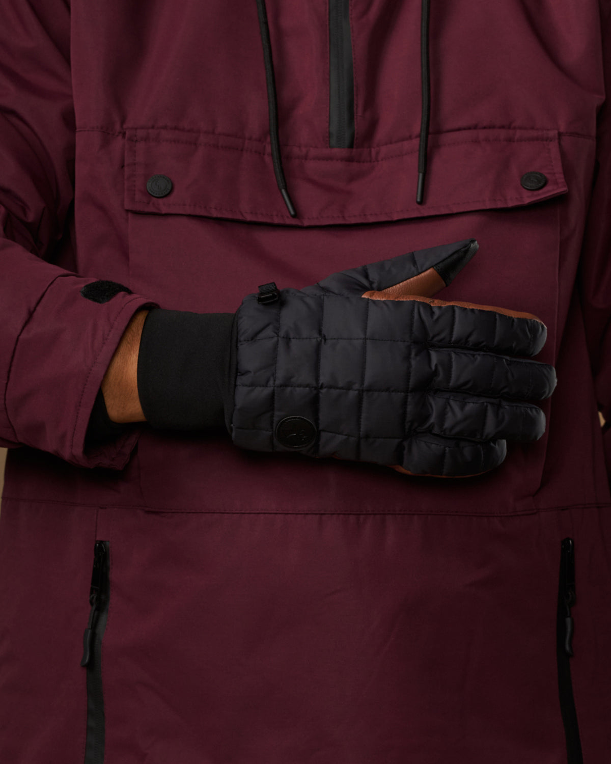 Close-up of men's quilted touchscreen gloves, dark gray with brown details