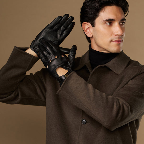 Pair of black driving gloves showing stud accents and elastic wrist fit