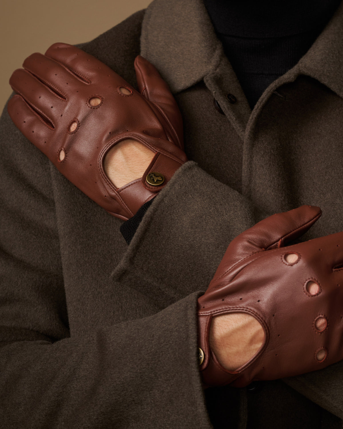 Brown leather driving gloves close-up with elastic wrist and touchscreen patch
