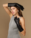 Black leather below-elbow gloves with ruched cuffs and touchscreen fingertips, glossy