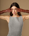 Cognac leather below-elbow gloves, fingers stretched across the frame