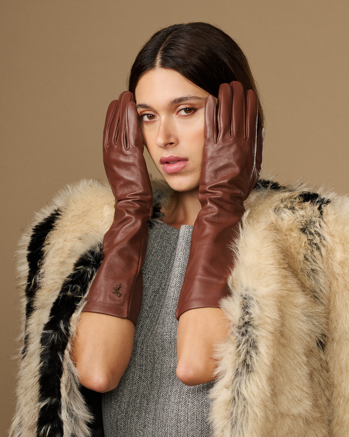 Women's brown below-elbow leather gloves with silk lining, close hands near face