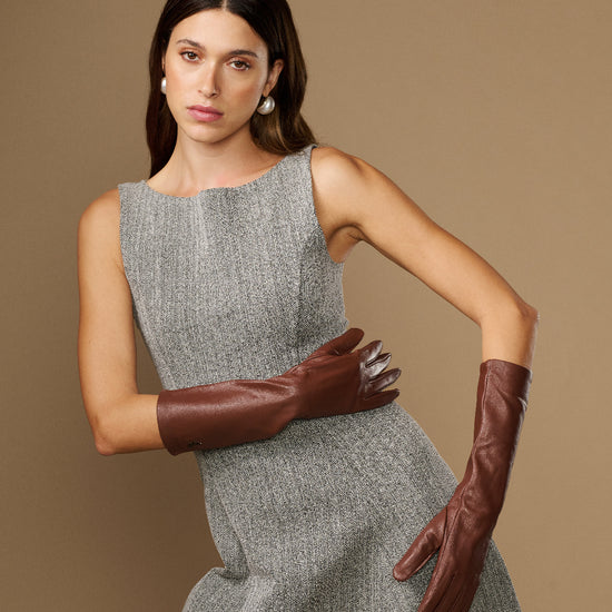 Women's brown below-elbow leather gloves with silk lining, cross-armed pose