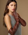 Women's chocolate-brown lambskin leather gloves, side view on raised hands with finger detailing