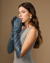 Dark blue elbow-length leather gloves on model, one glove raised