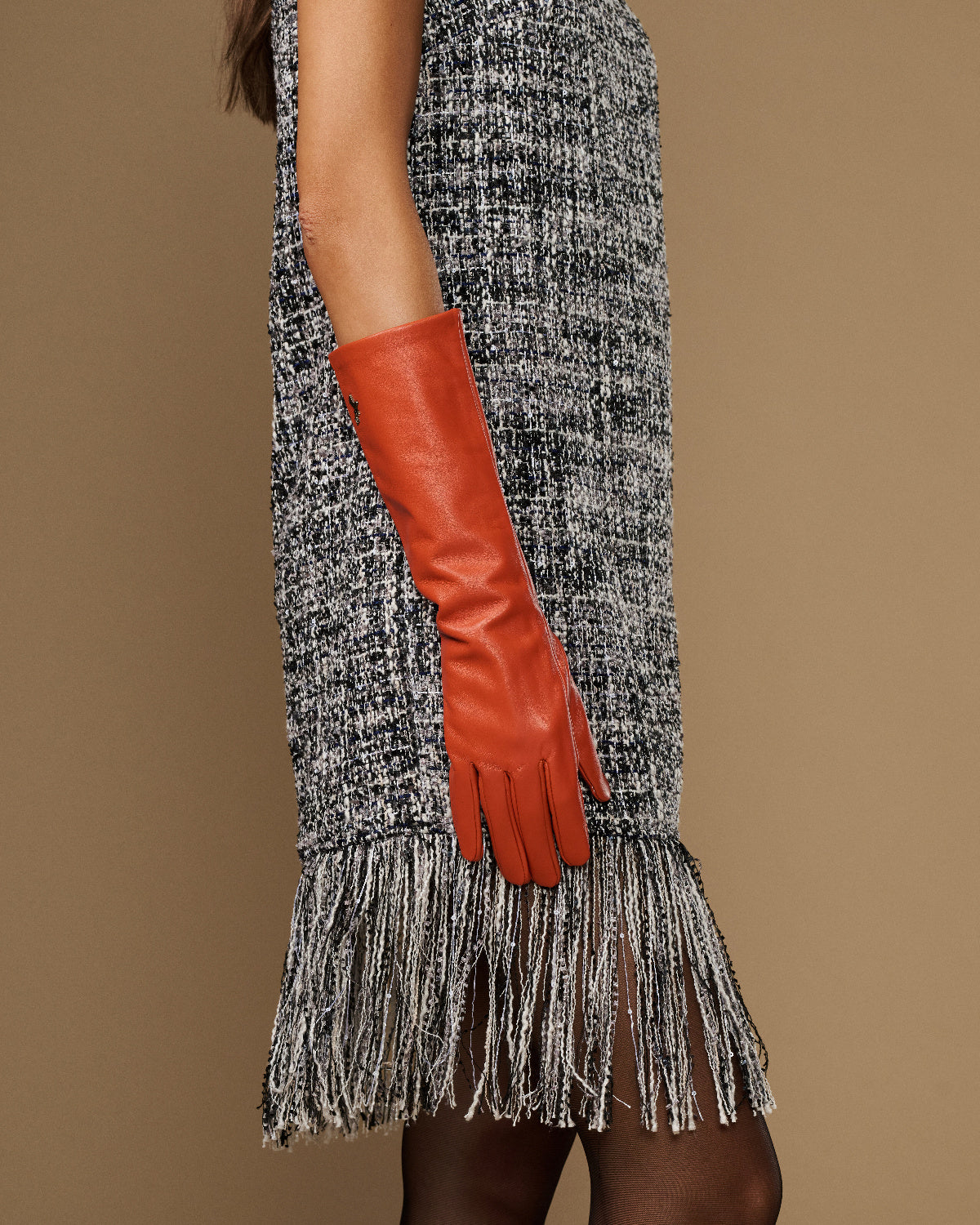 Women’s orange leather glove on raised arm, below-elbow length and tapered hand