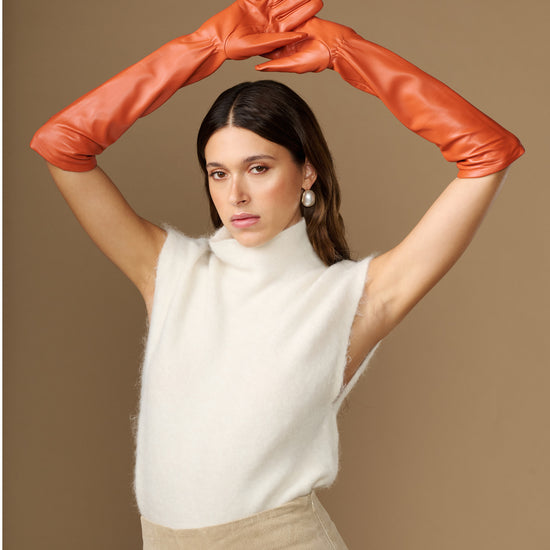 Orange leather elbow gloves worn with arms raised, covering hands and forearms