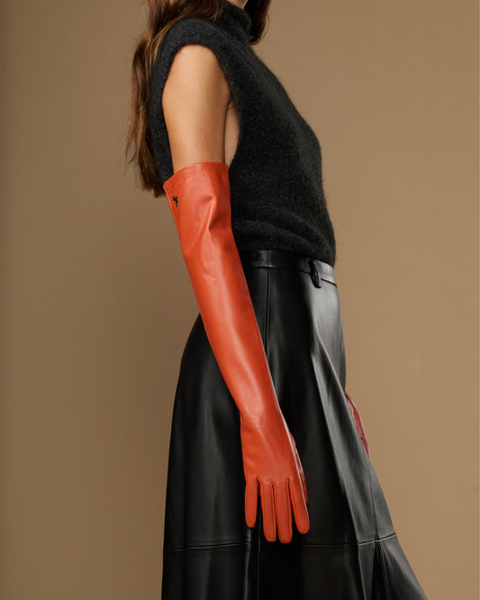 Orange leather gloves with fitted cuffs; silk lining and touchscreen feature visible on wrist
