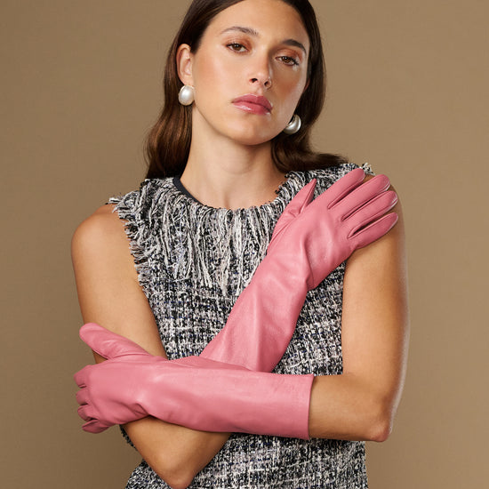 Pink below-elbow leather gloves, smooth fitted style, arms crossed with gloves visible