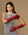 Red leather gloves worn on both arms, featuring snug wrist cuffs and tailored fingers