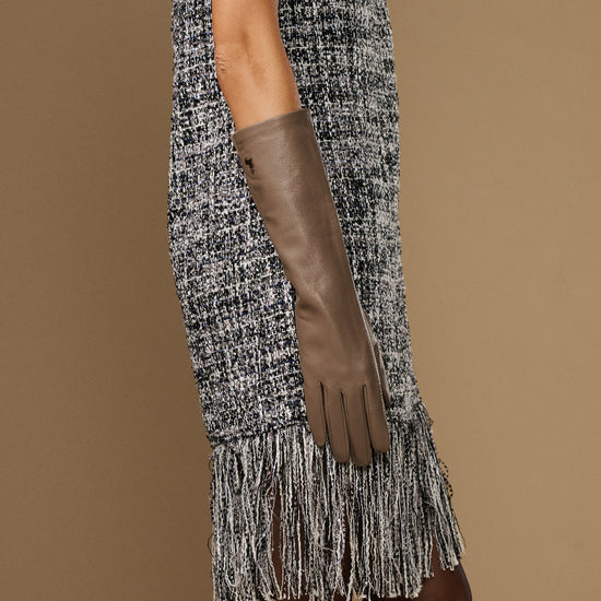 Taupe below-elbow leather glove on arm, long slim cuff with finger seams visible.