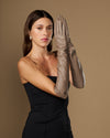 Taupe lambskin elbow-length leather gloves, model holding one glove up