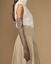 Taupe leather glove on one hand with long opera cuff and finger seams