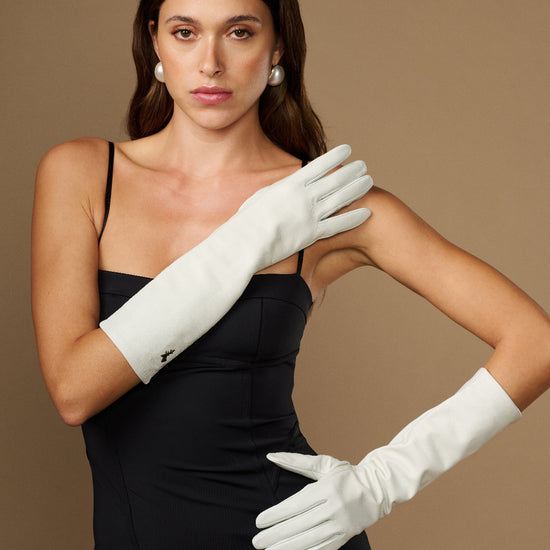 Women’s white lambskin leather below-elbow gloves, silk-lined, worn together on hands