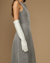 White elbow-length leather glove on arm, showing long cuff and finger seams