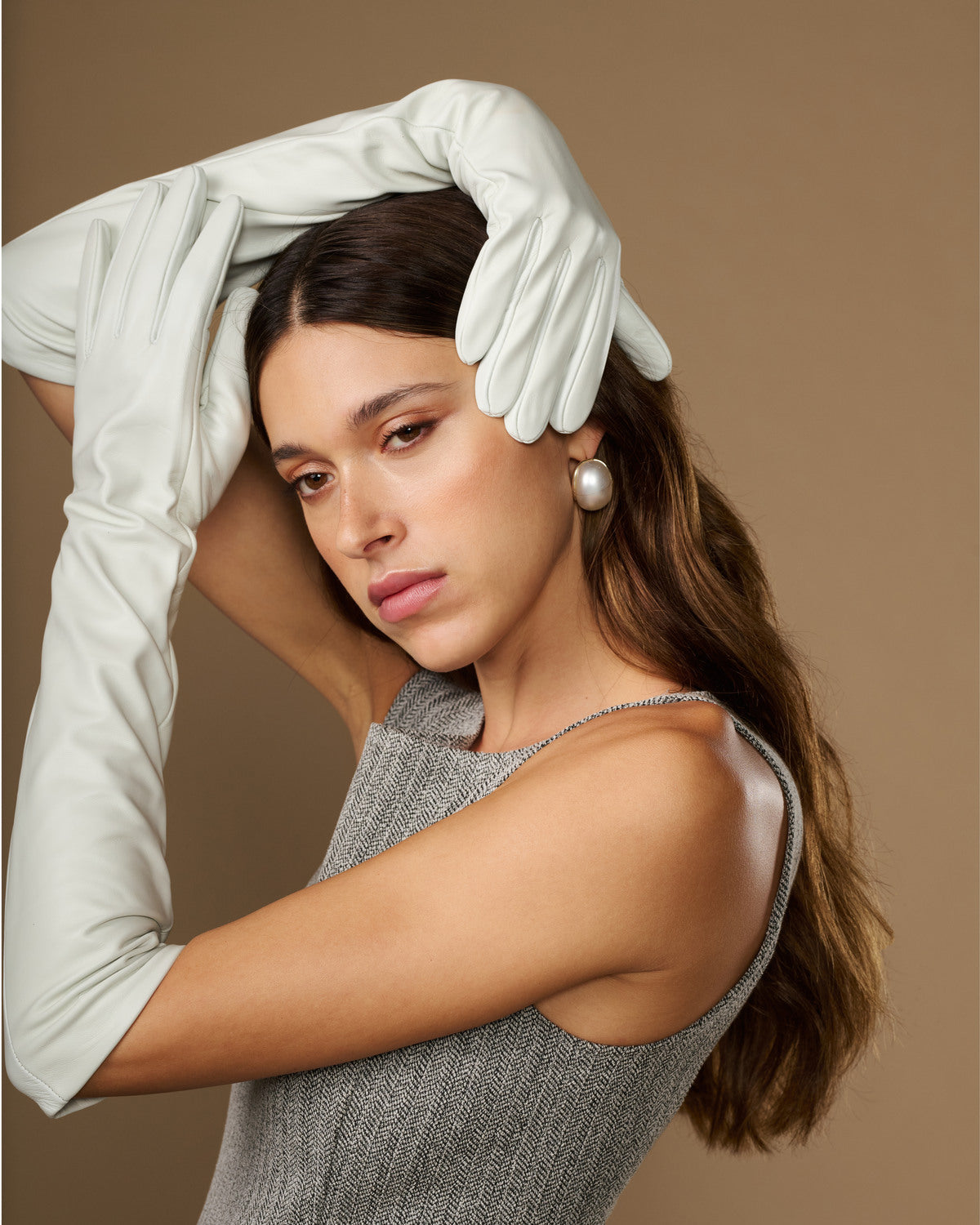 White elbow-length leather gloves worn on raised arms, smooth fingers and cuff
