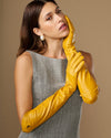 Yellow leather elbow gloves with glossy sheen and logo on wrist