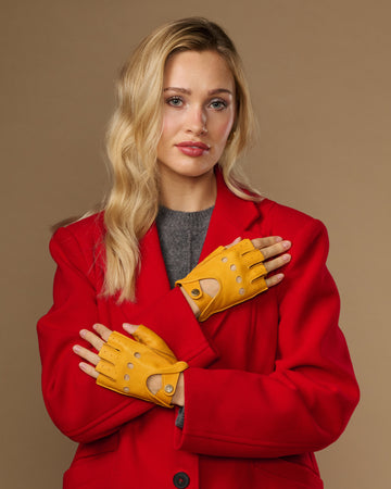 Yellow women's fingerless lambskin driving gloves with stitched finger holes and studs