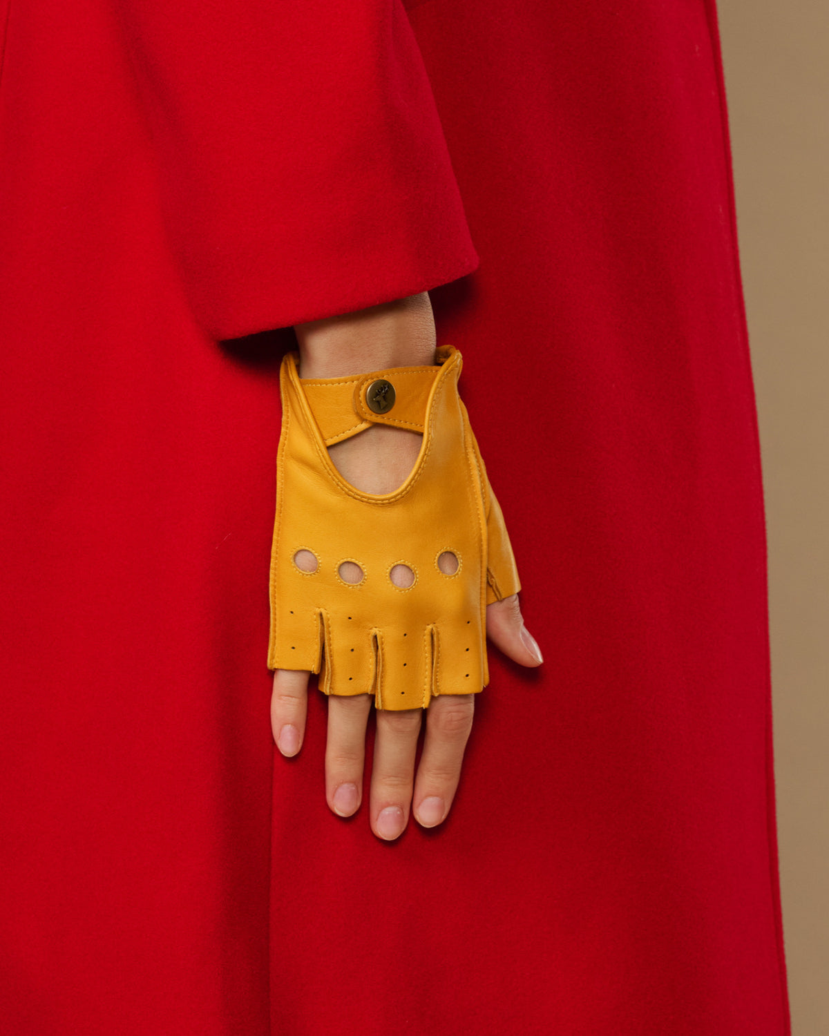 Yellow fingerless lambskin glove with thumb opening, snap cuff, and perforation panels